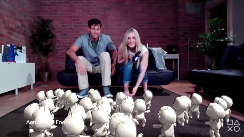 man and woman on a sofa playing with small white robots in vr