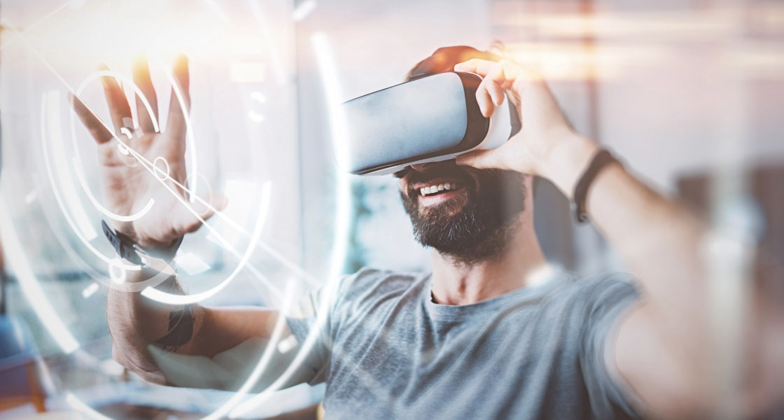 smiling bearded man wearing vr headset touching a hologram