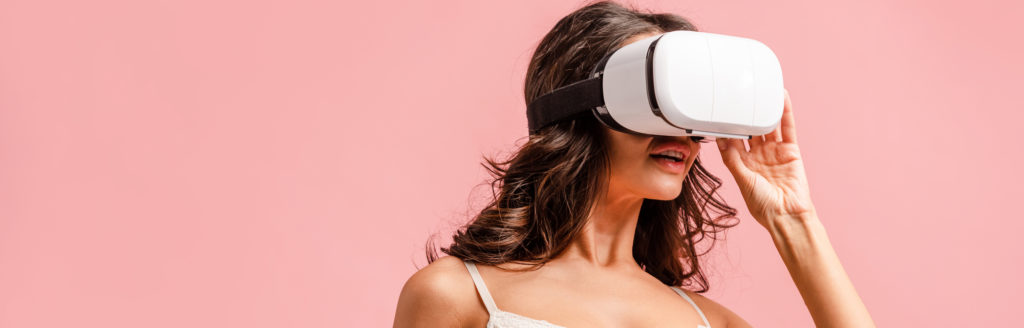 A beautiful woman in a spaghetti strap tank top with VR goggles on