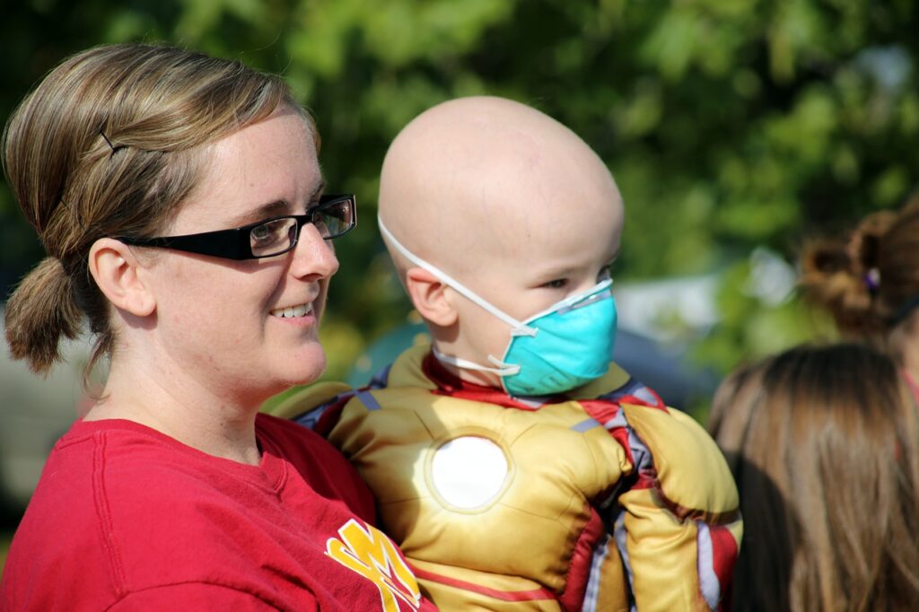 mother carrying her kid with cancer wearing superhero costume