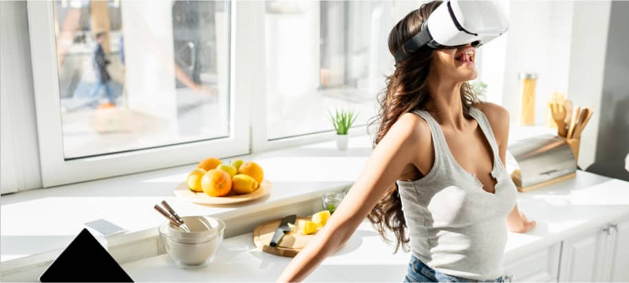 img young woman in denim shorts sticking out tongue while using vr headset near laptop and credit card